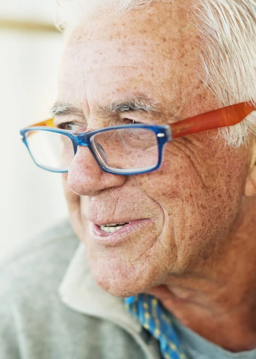 An older man with white hair and glasses caught in conversation with a carer at home