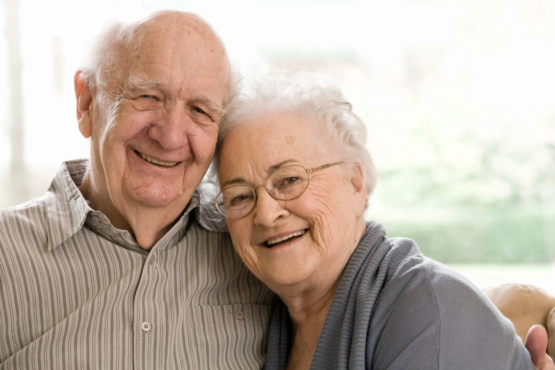 Elderly Man and Woman Sitting on Couch smiling to the camera