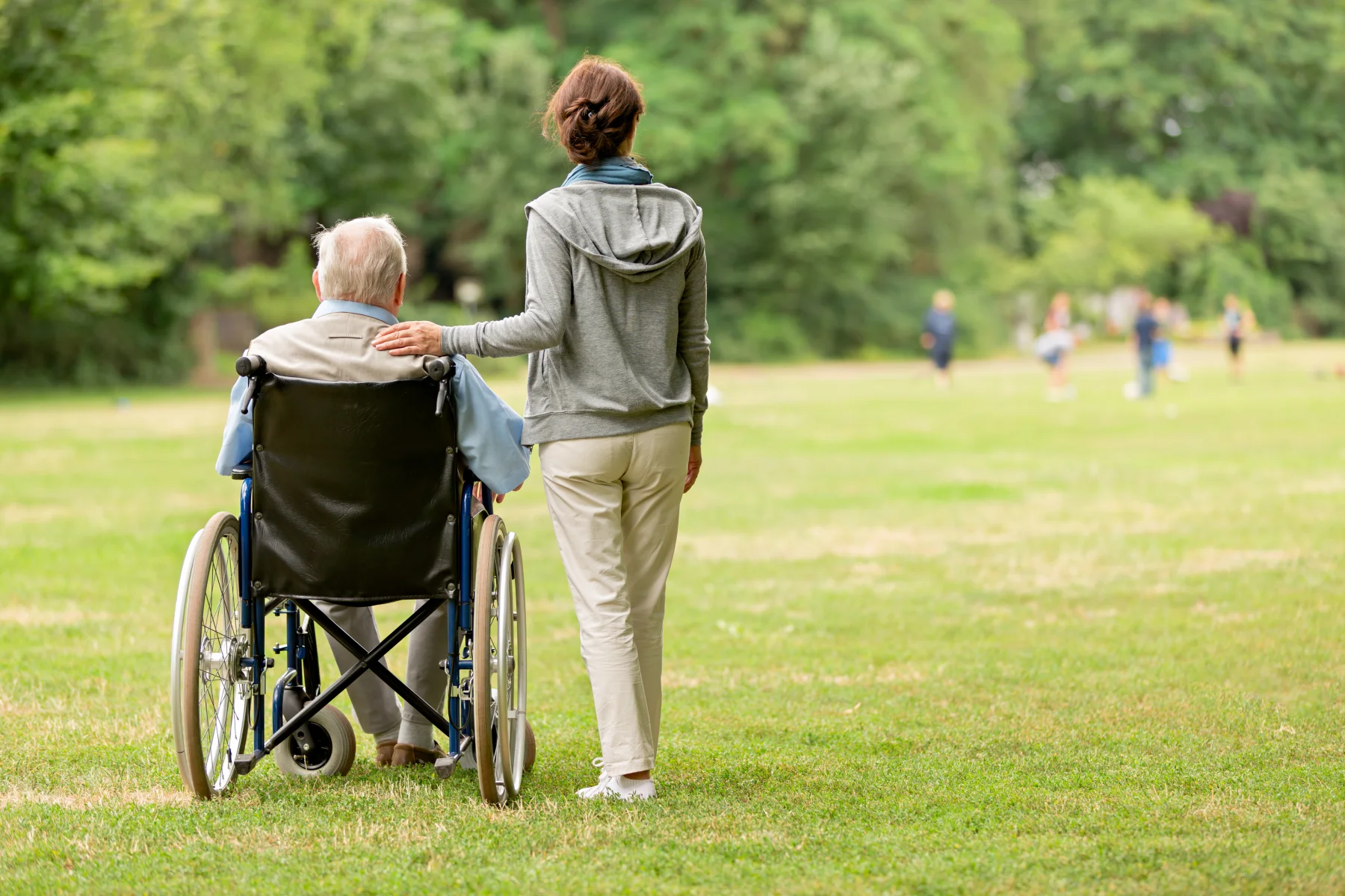 Senior man in a wheelchair with caregiver at the park