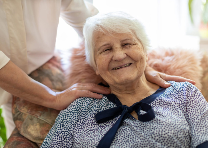 Woman spending time with her elderly mother who is smiling at the camera