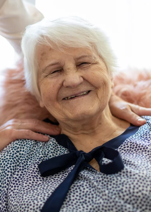Woman spending time with her elderly mother who is smiling at the camera