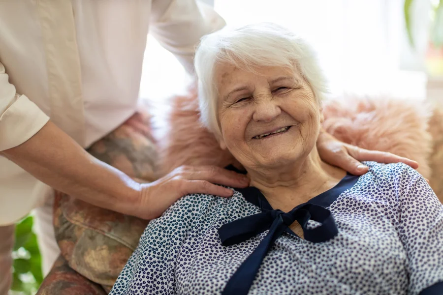 Woman spending time with her elderly mother who is smiling at the camera