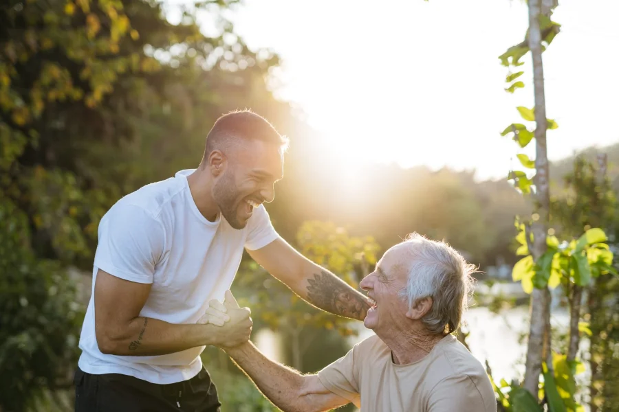 Young carer and older gentlemen greet each other in a park