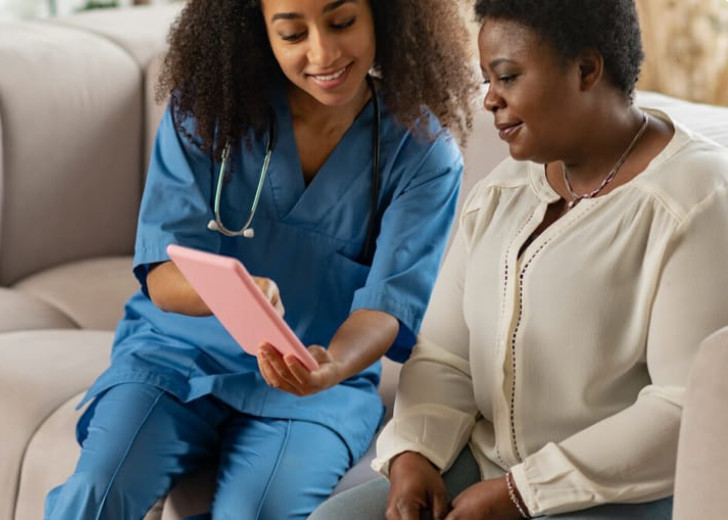 A home care nurse and client viewing something on a tablet together
