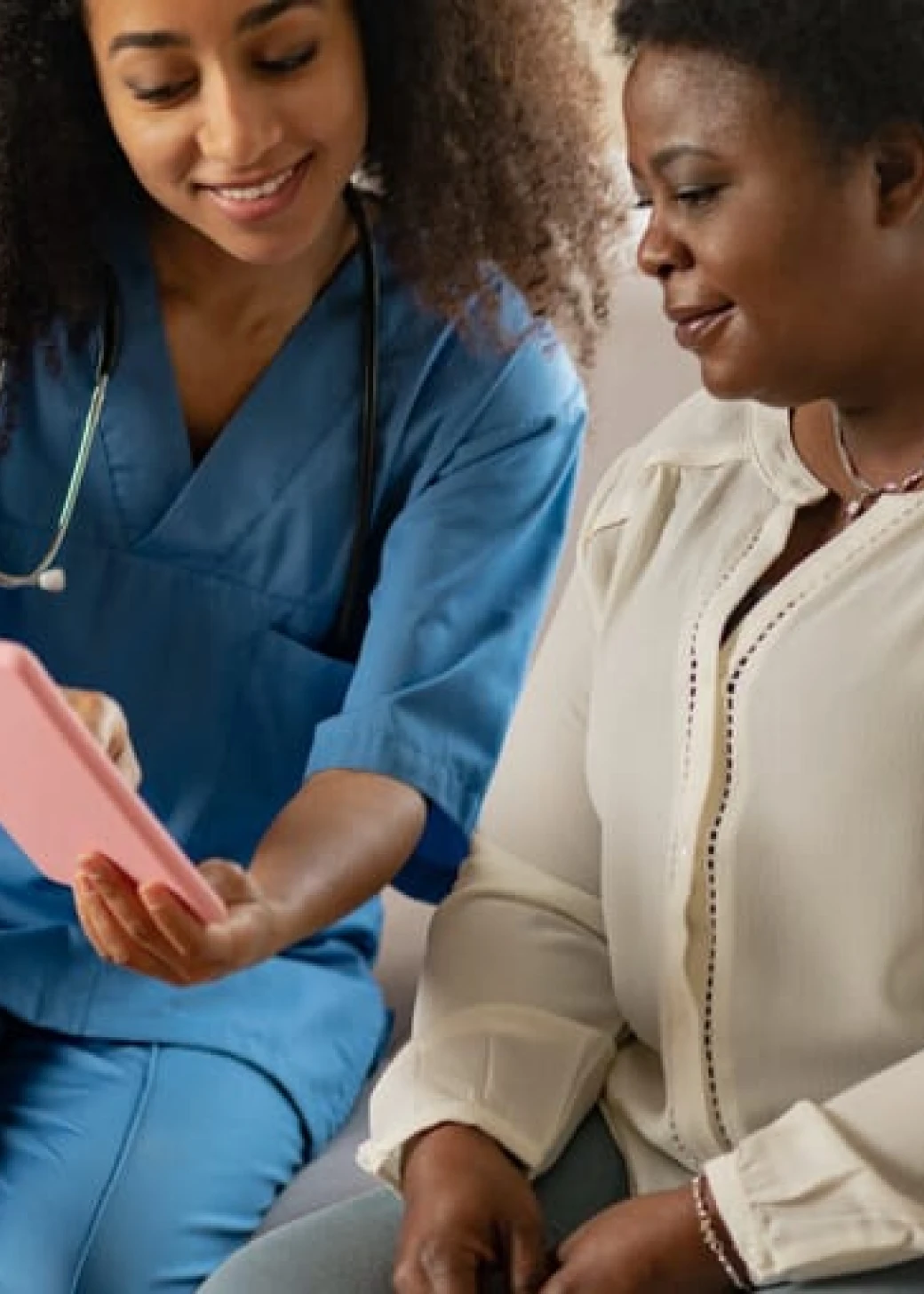 A home care nurse and client viewing something on a tablet together