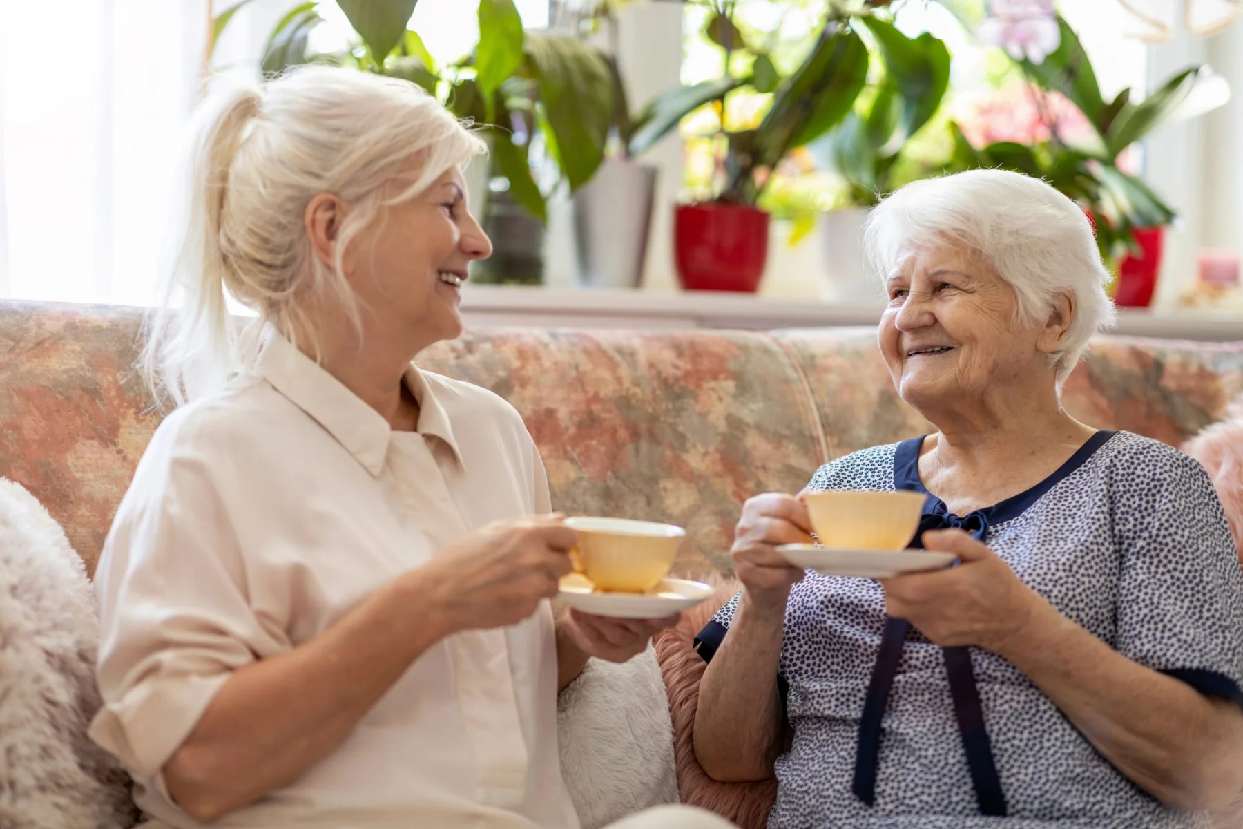 Woman spending time with her elderly mother at home having a cup of tea